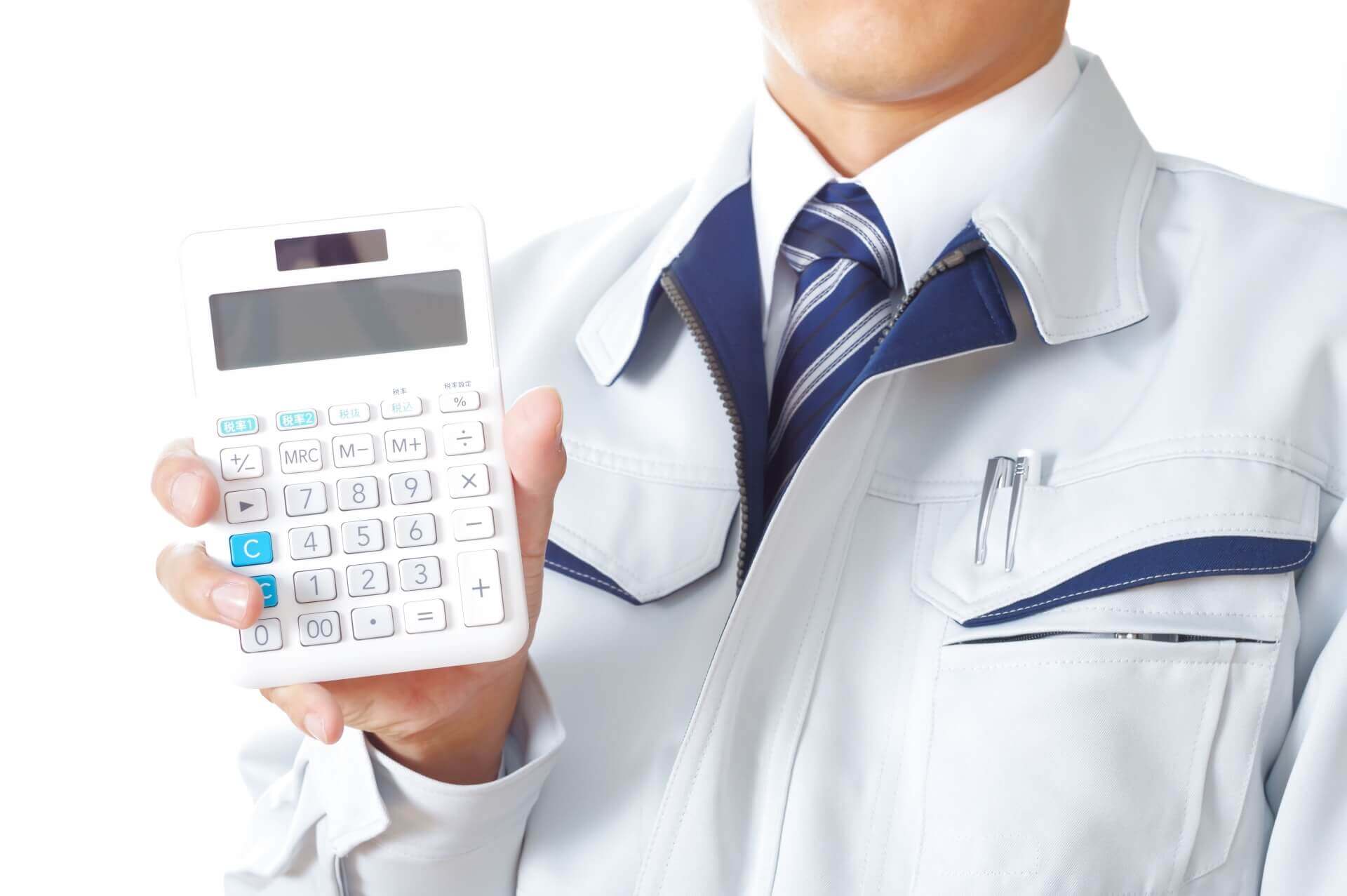 電卓を持つ作業服の技術者の手元