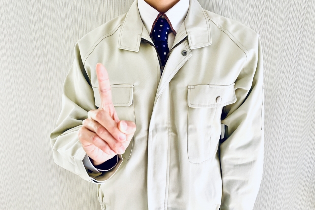 指を立てる作業服の男性